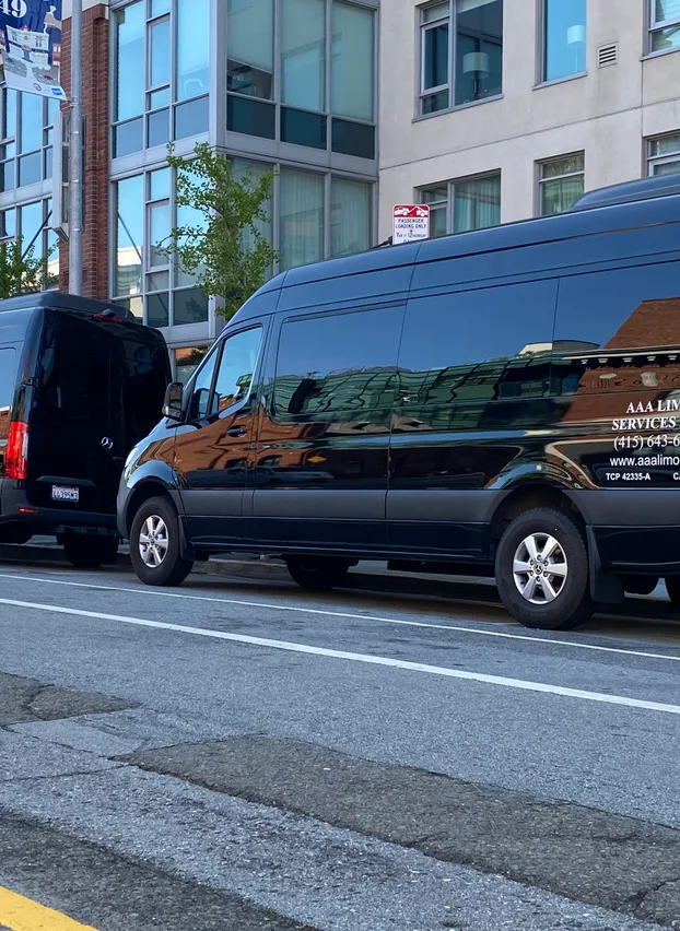 Two branded AAALIMO Mercedes-Benz Sprinters staged at a passenger loading zone on a San Francisco street